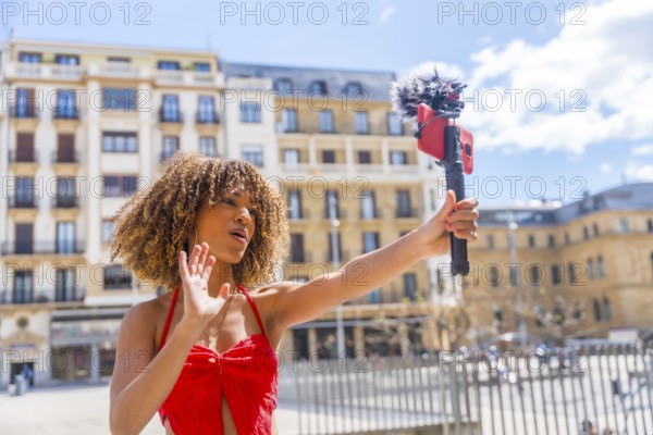 Brunette woman recording life video streaming with mobile outdoors in the city