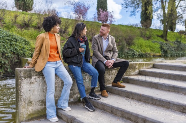 Three young professionals enjoying a conversation and coffee by a canal after work, representing work life balance and urban lifestyle