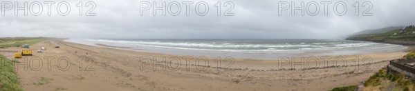Wide sandy beach with waves under a cloudy sky, coastal panorama, quiet atmosphere, Inch Beach