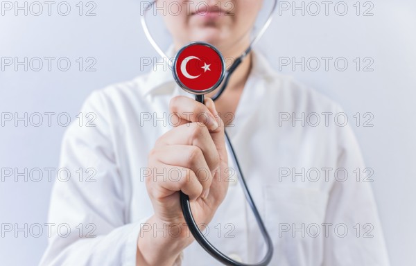 Female doctor holding stethoscope with Turkey flag. National Health System of Turkey