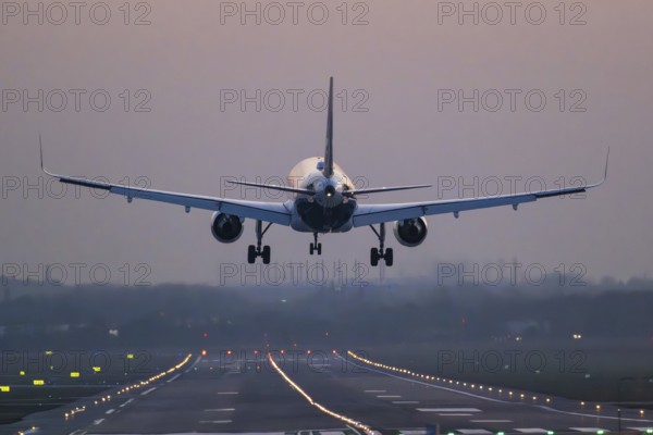 An aeroplane lands on an illuminated runway at dusk, Helmut Schmidt Airport, Fuhlsbüttel Airport, Hamburg, Germany, Europe