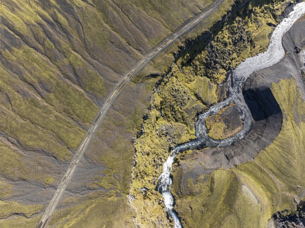 River along road F232 Öldufellsleid, slopes of Mt. Öldufell, moss-covered hill in black lava sand, aerial view, Iceland, Europe