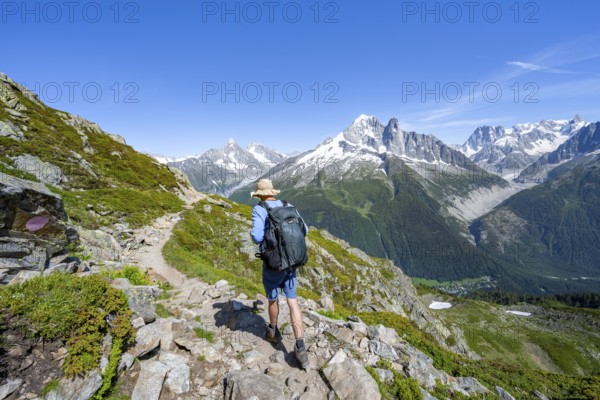Mountaineer on a hiking trail in front of a mountain landscape, view of the mountain peaks Aiguille Verte and Grandes Jorasses of the Mont Blanc massif, Aiguilles Rouges, Chamonix-Mont-Blanc, Haute-Savoie, France, Europe
