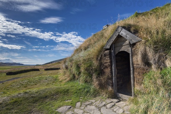 Traditional turf house with wooden door and grass roof in the sunshine, replica of a Viking longhouse, home of Eiríkr Þorvaldsson or Erik the Red, Eiríksstaðir, Iceland, Europe