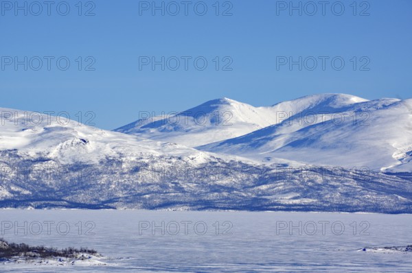 Snow-capped mountains and a frozen lake under a clear blue sky, Abisko, Abisko National Park, Torneträsk, Lapland, Sweden, Europe