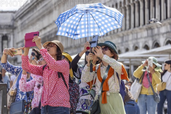 Tourists from Asia with mobile phones and parasols taking photos. Souvenir photo of St Mark's Square, Venice, Venice, Italy, Europe
