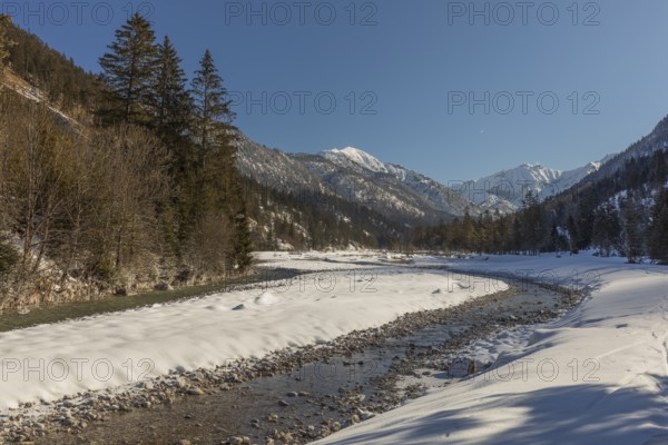 The Riss creek flowing through a snow covered landscape in the Eng valley. Sunny day with blue sky