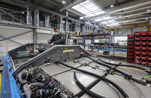 Herten, North Rhine-Westphalia, Germany, Cummins Hydrogenics fuel cell factory. An employee assembles fuel cell systems for Alstom's Coradia iLint hydrogen trains. The Coradia iLint is the world's first passenger train to be powered by a hydrogen fuel cell, which generates electrical energy for propulsion. Six fuel cell modules are installed in each train (right in the picture) . Note: The person pictured has given their verbal consent for publication in the press, Europe