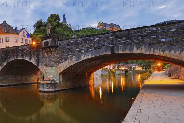 Town view of Vianden with the old stone bridge over the river Our and the castle in the evening, Grand Duchy of Luxembourg
