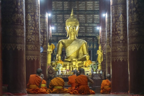 Monks praying in front of the great Buddha in the temple Wat Pak Khan Khammungkhun, Luang Prabang, Laos, Asia