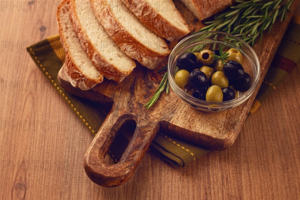 Sliced ciabatta, on a chopping board, with rosemary and olives, Italian bread, close-up, Italian cuisine, breakfast, no people