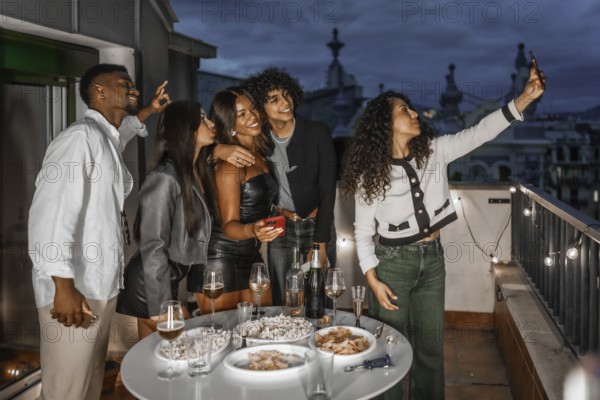 Woman taking selfie during night party in a rooftop with multi-ethnic friends
