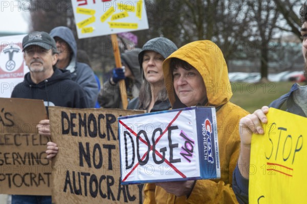 Troy, Michigan USA - 29 March 2025 - People gathered in the rain outside the Tesla Showroom at the Somerset Mall to protest Tesla owner Elon Musk's role in slashing government services. It was one of many 'Tesla Takedown' actions planned around the country and abroad