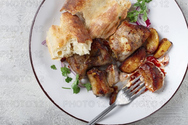 A plate with leftover pork kebab, with bread, on a white plate, close-up, there are no people
