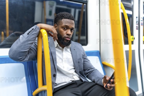 Young businessman engaging with smartphone while commuting on subway train, navigating messages and apps during busy urban journey