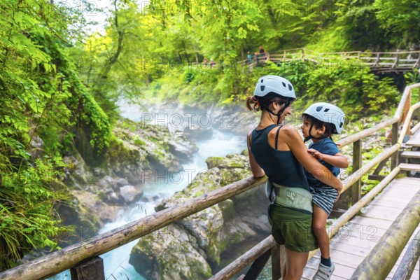 Mother holding her son while enjoying the breathtaking view of the turquoise radovna river flowing through the vintgar gorge near bled, slovenia