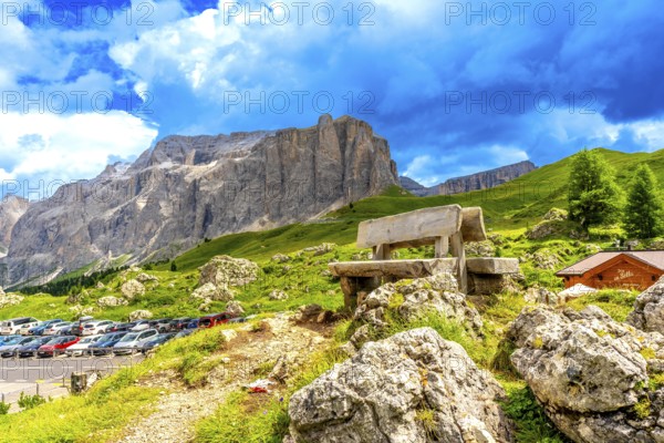 Weathered wooden bench inviting rest while offering breathtaking views of sella pass in the italian dolomites