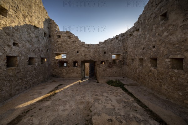 Stone ruin with sunlight through the entrance, surrounded by historic walls, Pag, Croatia, Europe