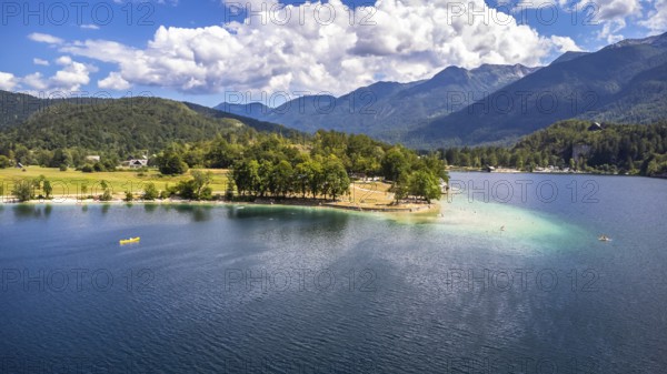 Aerial view of tourists enjoying summer holidays, swimming and kayaking on the beautiful lake bohinj, surrounded by the julian alps in slovenia