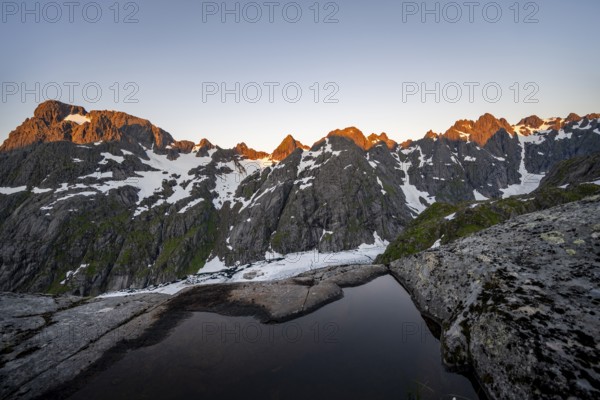 Rocky mountain peaks and Trollfjordvatnet with snow, small pond in moorland at Trollfjord Hytta, mountain landscape with alpenglow at sunrise, at Trollfjord, Lofoten and Vesterålen, Nordland, Norway, Europe