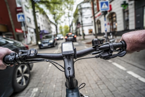 Cycling in the city, inner-city street, cycle lane, bicycles have priority, two-lane traffic with parked cars on both sides, cyclists' perspective, Essen, North Rhine-Westphalia, Germany, Europe