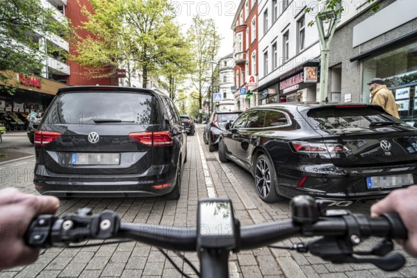 Cycling in the city, inner-city street, cycle lane, bicycles have priority, two-lane traffic with parked cars on both sides, cyclists' perspective, Essen, North Rhine-Westphalia, Germany, Europe