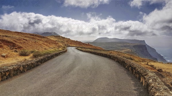 Serpentine road in a barren mountain landscape with clouds in the sky near the Mirador del Rio, Lanzarote, Canary Islands, Spain, Europe