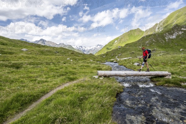 Mountaineer crossing a stream on a tree trunk, mountain landscape with mountain stream, Lasörling Group, Hohe Tauern National Park, East Tyrol, Austria, Europe