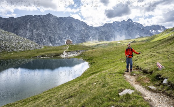 Mountaineers on a hiking trail, rocky mountain peaks of the Panargenkamm and Neue Reichenberger Hütte with mountain lake Bödensee, Lasörlinggruppe, Hohe Tauern National Park, East Tyrol, Austria, Europe