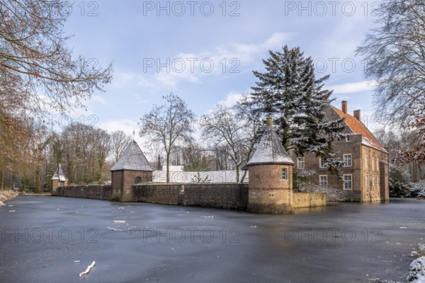Moated castle Haus Welbergen surrounded by frozen water and snow-covered trees, Ochtrup-Welbergen, Münsterland, North Rhine-Westphalia, Germany, Europe
