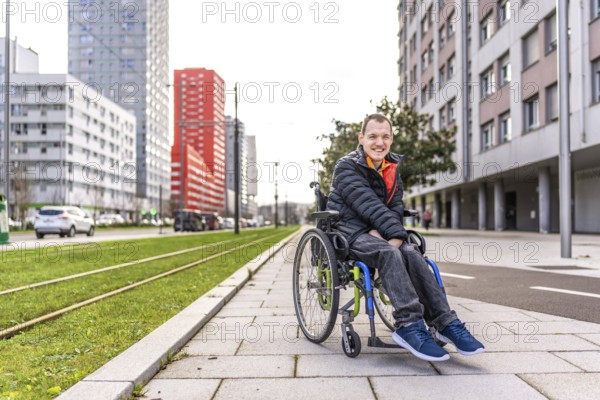 Portrait of a happy young man with disability in a wheelchair enjoying a sunny day in the city