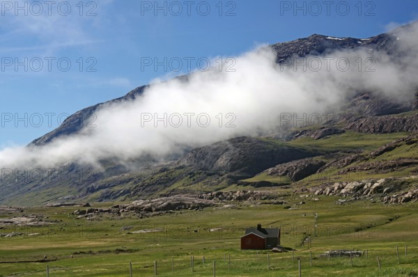 House in a green meadow with mountains and clouds above, blue sky, Igaliku, North America, Greenland, Denmark, North America