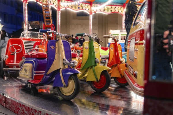 Colourful toy scooters on a fairground carousel at night, Christmas market Ludwigsburg, Germany, Europe