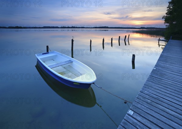 Sunset at Lake Schaalsee, jetty with rowing boat and wooden post in the water, Schaalsee Biosphere Reserve, Zarrentin am Schaalsee, Mecklenburg-Western Pomerania, Germany, Europe