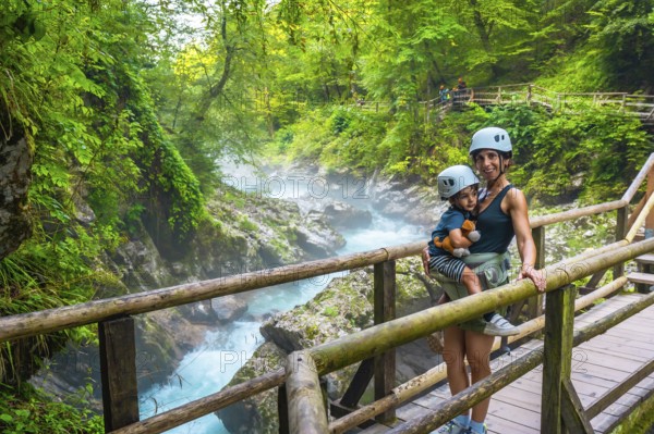 Mother carrying her child while visiting the stunning vintgar gorge near bled, slovenia, enjoying a breathtaking view of the turquoise river and lush forest