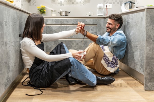 Chefs enjoying a coffee break, holding hands and smiling at each other, sitting on the kitchen floor