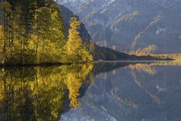 Lake Almsee in autumn with mountains reflected in the lake. Blue sky