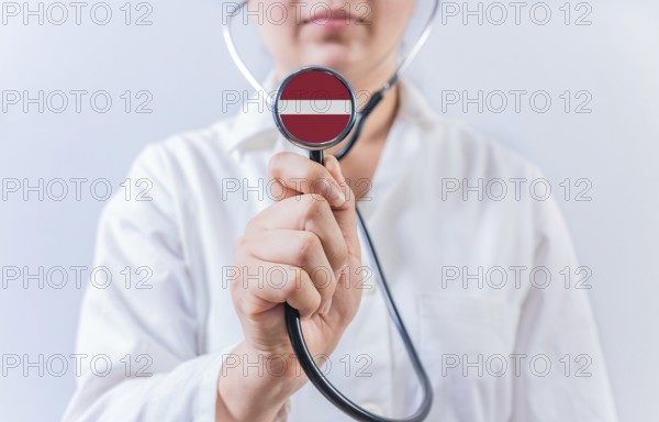 Female Doctor Holding Stethoscope With Latvia Flag. National Health System Of Latvia