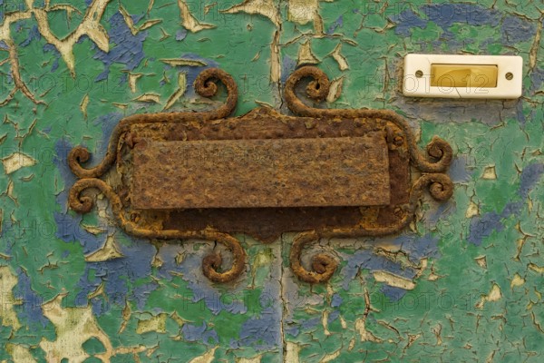 Close-up, old shabby dilapidated front door with antiquated rusty mail slot and yellowed doorbell in the historic centre of Cervo, province of Imperia, Liguria, Italy, Europe