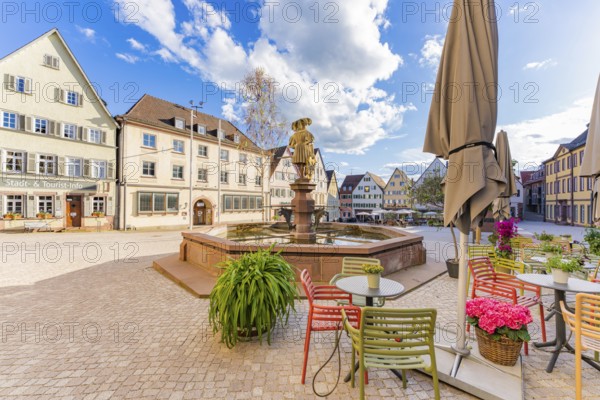 A lively town square with colourful chairs and tables next to a fountain under a clear sky, Weil der Stadt, Böblingen district, Germany, Europe