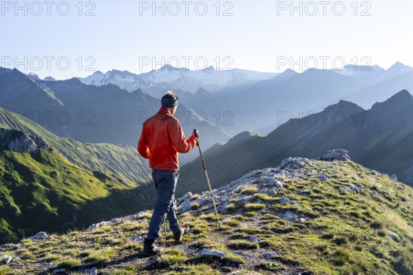 Hiker enjoying the mountain panorama in the morning, Venediger group, behind Dreiherrenkopf, Simonysitze and Großer Geiger, Hohen Tauern, Austria, Europe
