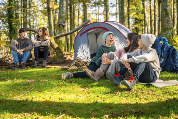 Caucasian family with three children sitting enjoying nature during a day camping at forest