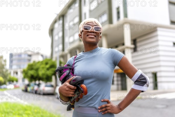 Blonde african woman posing proud holding inline skates standing in the city street