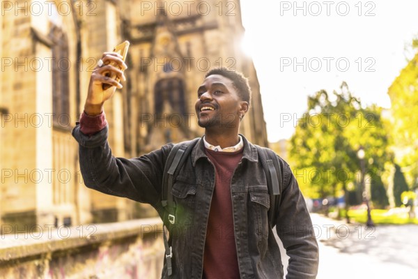 Happy african man walking along the city taking photos under the sunset
