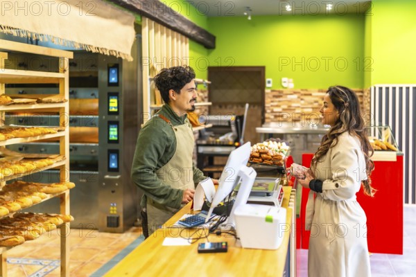 Elegant latin woman talking to salesman in a modern and artisan bakery