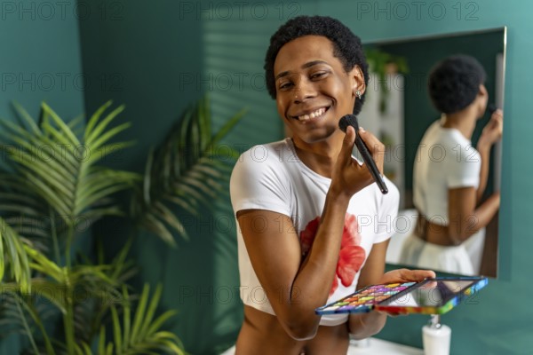 Portrait of a latin happy transgender person applying makeup in the bathroom at home