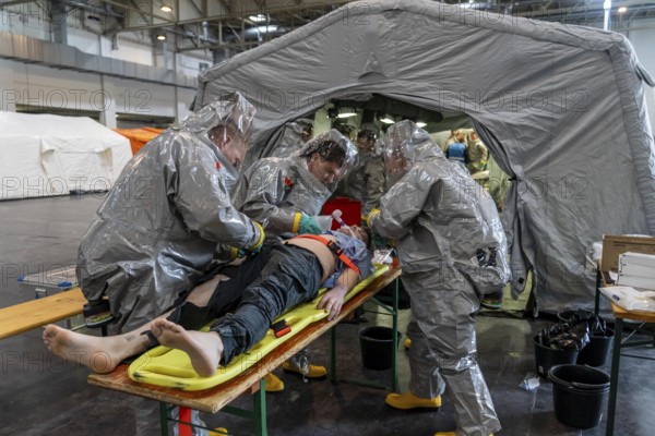 Decontamination of injured persons after an assumed accident involving hazardous substances, fire brigade and aid organisations practise setting up and operating a decontamination station, injured persons are sighted and then washed in a special shower tent to remove possible hazardous substances and chemicals in order to avoid further injuries, the emergency services wear special, ventilated protective suits, large-scale exercise by the Essen fire brigade