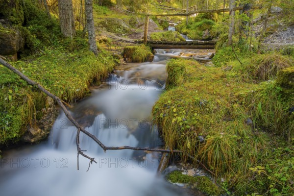View of a wooden bridge leading over a torrent, long exposure, Dolomites, Puez-Geisler nature park Park, St. Magdalena, Funes, Villnößtal, South Tyrol, Italy, Europe