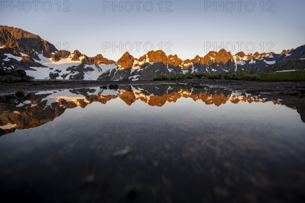 Rocky mountain peaks reflected in a small pond, mountain landscape with alpenglow at sunrise, at the Trollfjord Hytta, at the Trollfjord, Lofoten and Vesterålen, Nordland, Norway, Europe