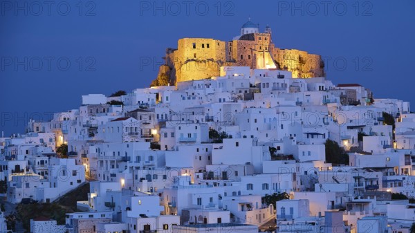 Whitewashed buildings surround an illuminated fortress under a dark blue night sky, Querini Castle, Chora, Astypalea, Dodecanese, Greek Islands, Greece, Europe
